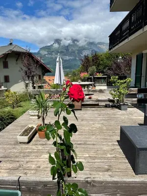 a wooden deck with a table and a white umbrella at Belle Vue de St Gervais in Saint-Gervais-les-Bains