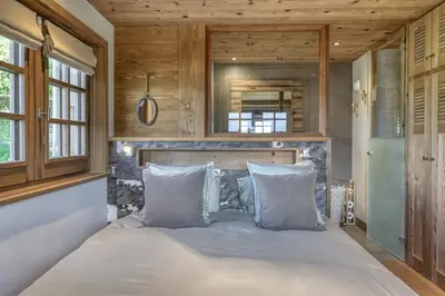 a large bed in a room with wooden walls at Chalet Carline in Combloux