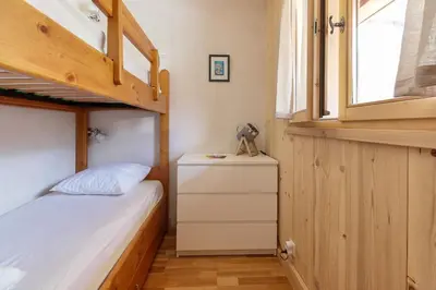 a small bedroom with a bunk bed and a dresser at Les Alpages - Newly Renovated - 2bed - Equipment Storage - Mont-Blanc Views in Les Houches