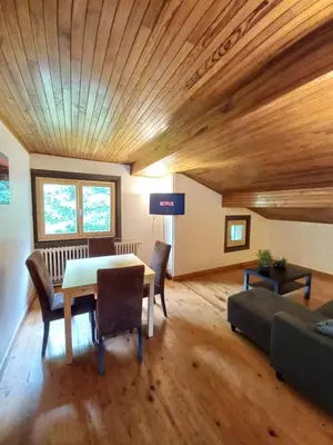 a living room with a table and a couch at Logement mansardé dans maison avec jardin en bord de piste, vue montagne in Les Houches