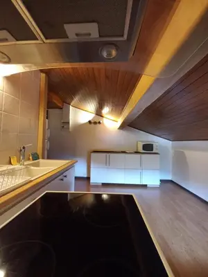 a kitchen with white cabinets and a wooden ceiling at Logement mansardé dans maison avec jardin en bord de piste, vue montagne in Les Houches