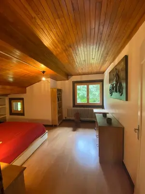a bedroom with a bed and a desk in it at Logement mansardé dans maison avec jardin en bord de piste, vue montagne in Les Houches