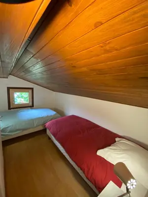 a bedroom with two beds and a wooden ceiling at Logement mansardé dans maison avec jardin en bord de piste, vue montagne in Les Houches