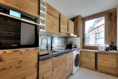 a kitchen with wooden cabinets and a washer and dryer at Appartement familial au pied de la télécabine 4* in Saint-Gervais-les-Bains