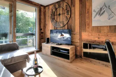a living room with a television and a clock on the wall at Appartement familial au pied de la télécabine 4* in Saint-Gervais-les-Bains