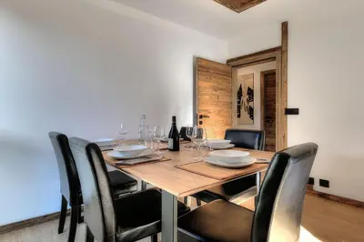 a dining room table with chairs and wine glasses at Appartement familial au pied de la télécabine 4* in Saint-Gervais-les-Bains