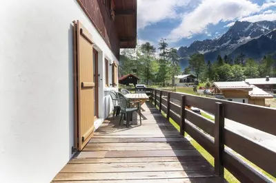a wooden porch with a table and chairs on a balcony at The Historic Chalet Les Allognes Mont-Blanc views in Les Houches