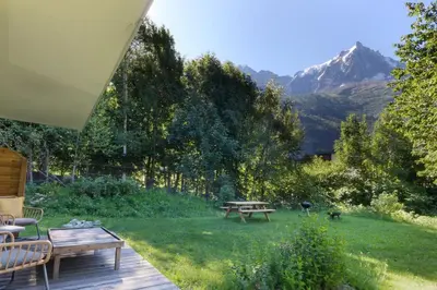 a patio with a table and a picnic table in the grass at Violette de Cham - Jardin privé - Vue Mont Blanc in Chamonix-Mont-Blanc