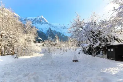 a snow covered yard with a mountain in the background at Violette de Cham - Jardin privé - Vue Mont Blanc in Chamonix-Mont-Blanc