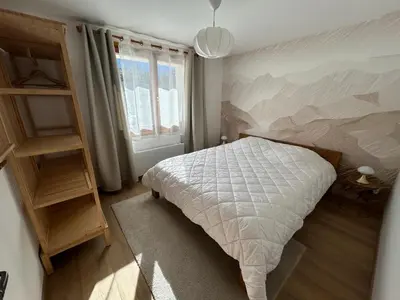 a bedroom with a bed with a painting on the wall at Violette de Cham - Jardin privé - Vue Mont Blanc in Chamonix-Mont-Blanc