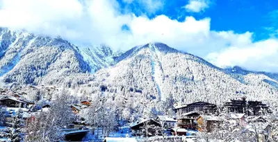 a mountain covered in snow with houses in the foreground at La Rivière - Aiguille du Midi in Chamonix-Mont-Blanc