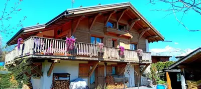 a log house with a balcony with flowers on it at Le chalet de Julbert in Combloux