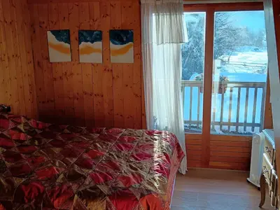 a bedroom with a bed and a large window at Le chalet de Julbert in Combloux