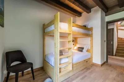 a bedroom with two bunk beds and a chair at Chalet Jatoba Chamonix - by EMERALD STAY in Chamonix-Mont-Blanc
