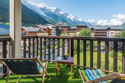 a balcony with chairs and a table and a view of a city at Joli appartement vue Mont Blanc 3 balcons et parking - Welkeys in Chamonix-Mont-Blanc