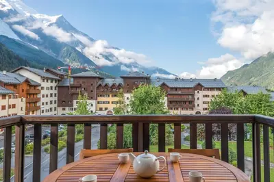 a table on a balcony with a view of mountains at Joli appartement vue Mont Blanc 3 balcons et parking - Welkeys in Chamonix-Mont-Blanc