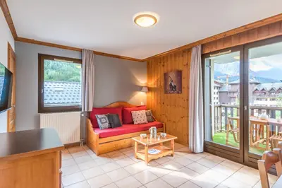 a living room with a red couch and a balcony at Joli appartement vue Mont Blanc 3 balcons et parking - Welkeys in Chamonix-Mont-Blanc