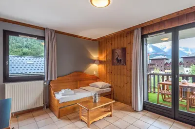 a room with a bed and a table and windows at Joli appartement vue Mont Blanc 3 balcons et parking - Welkeys in Chamonix-Mont-Blanc