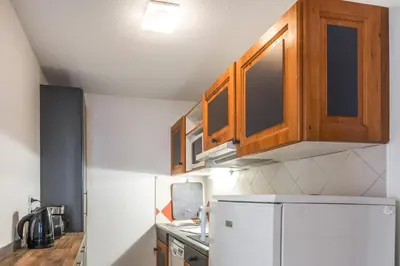 a kitchen with a white refrigerator and wooden cabinets at Joli appartement vue Mont Blanc 3 balcons et parking - Welkeys in Chamonix-Mont-Blanc