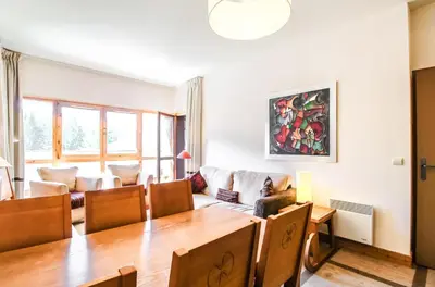 a dining room and living room with a table and chairs at Bright spacious two bed South facing family apartment in Flaine