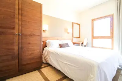 a bedroom with a white bed and a wooden closet at Bright spacious two bed South facing family apartment in Flaine
