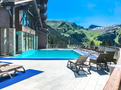 a swimming pool with mountains in the background at Bright spacious two bed South facing family apartment in Flaine