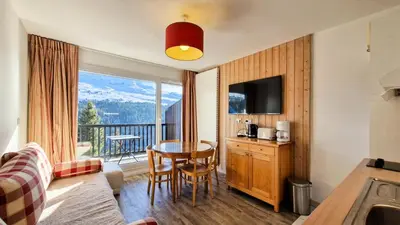 a hotel room with a table and a balcony at Résidence Les Pleiades - Appartement confortable · Centre station · Balcon · Parking couvert MAE-5454 in Flaine