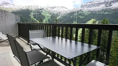 a table and chairs on a balcony with mountains at Résidence Les Pleiades - Appartement confortable · Centre station · Balcon · Parking couvert MAE-5454 in Flaine