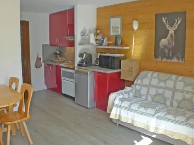 a kitchen with red cabinets and a couch in a room at Studio coquet avec terrasse, calme et parking à Samoëns - FR-1-629-86 in Samoëns