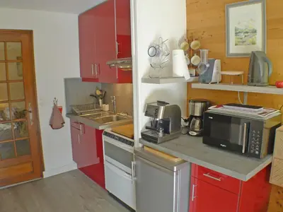 a kitchen with red cabinets and a microwave at Studio coquet avec terrasse, calme et parking à Samoëns - FR-1-629-86 in Samoëns