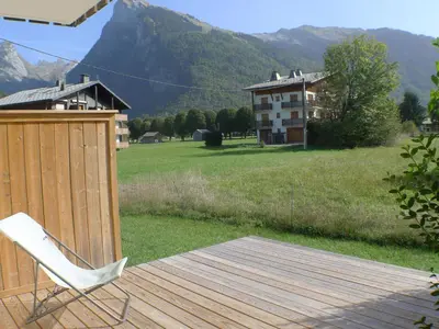a white chair sitting on a wooden deck with a house at Studio coquet avec terrasse, calme et parking à Samoëns - FR-1-629-86 in Samoëns