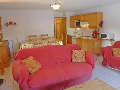 a living room with a red couch and a kitchen at Charmant T4 à Samoëns avec Balcon et Parking, 6 Pers. - FR-1-629-87 in Samoëns
