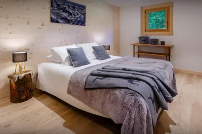 a bedroom with a large white bed with blue pillows at Chalet Les Vosnes - OVO Network in Domancy