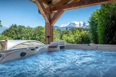 a hot tub in a backyard with a view of mountains at Chalet Les Vosnes - OVO Network in Domancy
