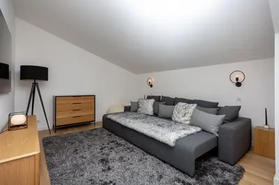 a living room with a gray couch and a tv at La Cordee 221 Penthouse - Chamonix All Year in Chamonix-Mont-Blanc