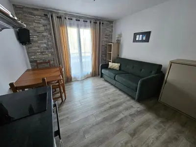 a living room with a green couch and a tv at Charmant Studio vue montagne - ski, piscine, tennis, randonnées in Saint-Gervais-les-Bains