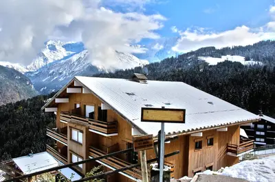 a ski lodge with a snow covered mountain in the background at Charmant Studio vue montagne - ski, piscine, tennis, randonnées in Saint-Gervais-les-Bains