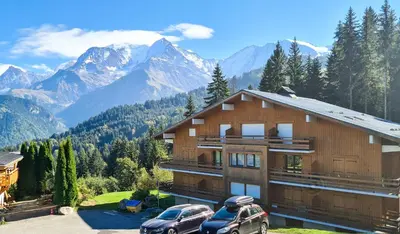 a house in the mountains with two cars parked in front at Charmant Studio vue montagne - ski, piscine, tennis, randonnées in Saint-Gervais-les-Bains