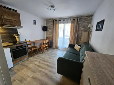 a living room with a couch and a kitchen and a table at Charmant Studio vue montagne - ski, piscine, tennis, randonnées in Saint-Gervais-les-Bains