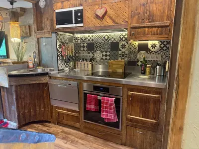 a kitchen with wooden cabinets and a stove top oven at le coup de coeur in Les Houches