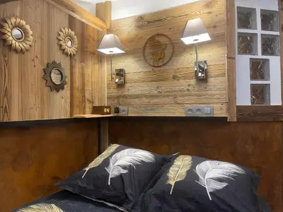 a bedroom with a wooden wall with a bed and two lights at le coup de coeur in Les Houches