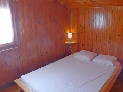 a bedroom with a white bed in a wooden wall at Chalet Gentiane - un lieu idéal pour des vacances en famille ou entre amis - FR-1-629-88 in Samoëns