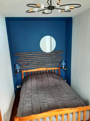 a bedroom with a wooden bed with a blue wall at Appartement avec terrasse centre samoens in Samoëns