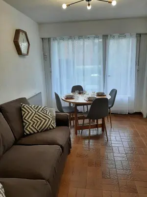 a living room with a couch and a table and chairs at Appartement avec terrasse centre samoens in Samoëns