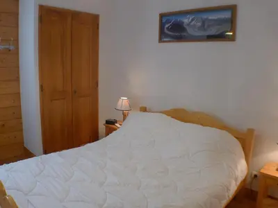 a bedroom with a white bed and a wooden door at Cosy, 3 pièces au centre, animaux admis, parking - FR-1-629-89 in Samoëns
