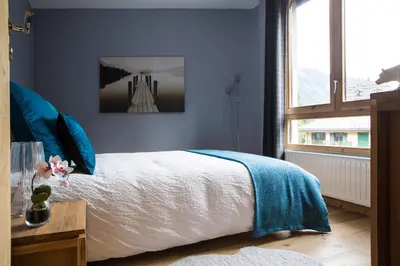 a bedroom with a bed with blue walls and a window at Le Beausite C Apartment - Chamonix All Year in Chamonix-Mont-Blanc