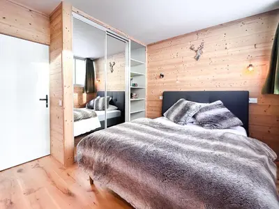 a bedroom with a large bed and wooden walls at Next to the pistes, 1-bedroom family apartment in Flaine