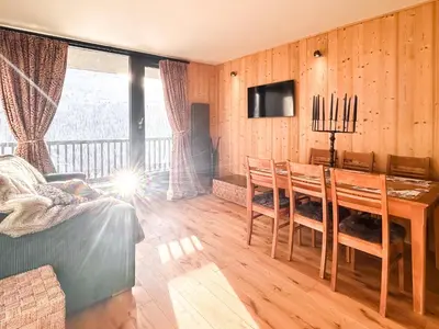 a dining room with a table and chairs and a television at Next to the pistes, 1-bedroom family apartment in Flaine