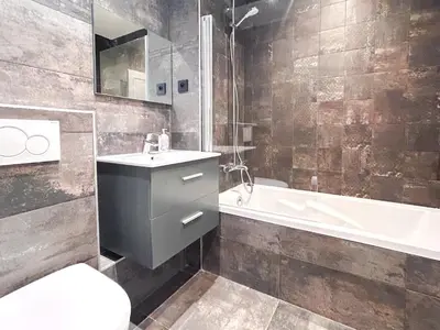 a bathroom with a sink and a tub and a toilet at Next to the pistes, 1-bedroom family apartment in Flaine