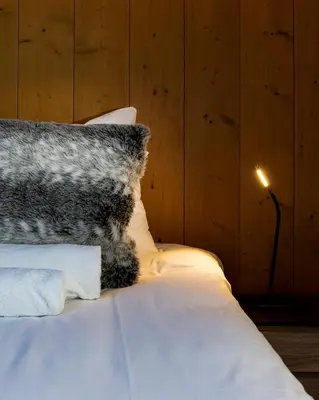 a bed with a black and white pillow and a lamp at La Snaille des Planards in Chamonix-Mont-Blanc